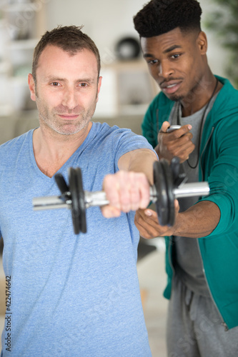 Εκτύπωση καμβά professional gym trainer motivating client to lift dumbbell