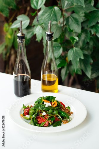 Italian shrimp salad with greens and tomato and the bottles of oil and sauce