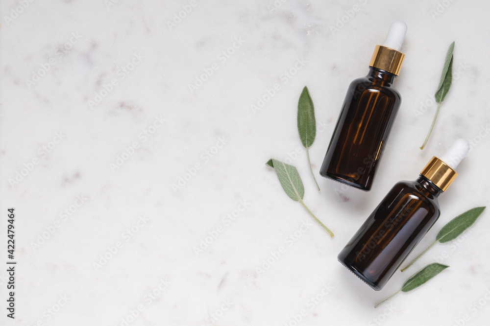 Cosmetic glass bottles with dark glass pipette on marble background with green leaf. Natural cosmetics concept Cosmetic glass bottles with dark glass pipette on marble background with green leaf. Natural cosmetics concept