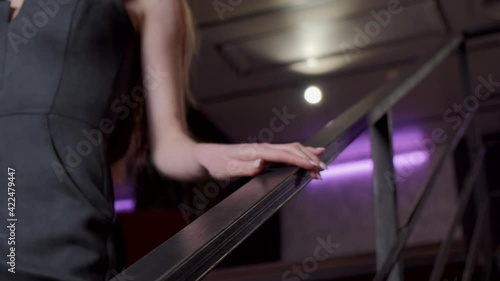 Caucasian woman wearing a black dress is going downstairs to a date