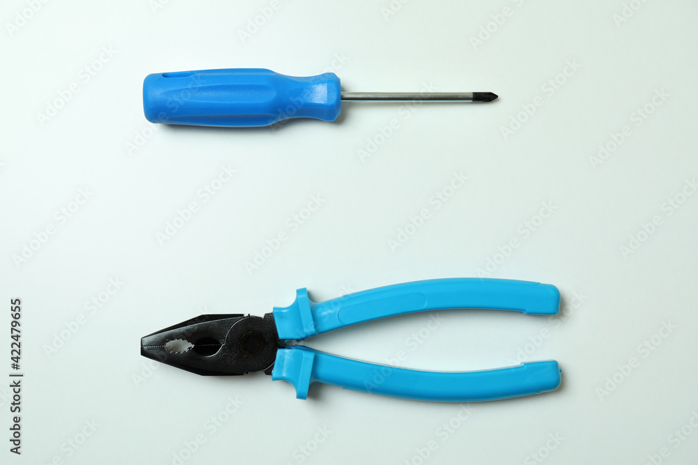 Screwdriver and pliers on white background, space for text