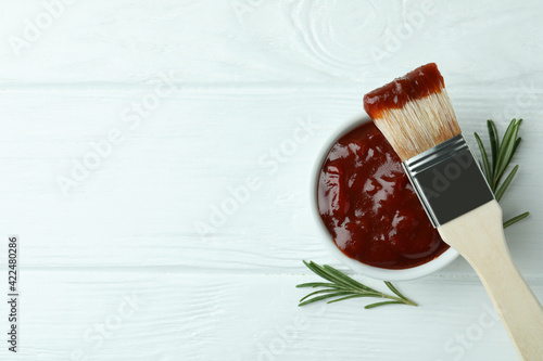 Slika na platnu Bowl of barbecue sauce with brush and rosemary on white wooden table