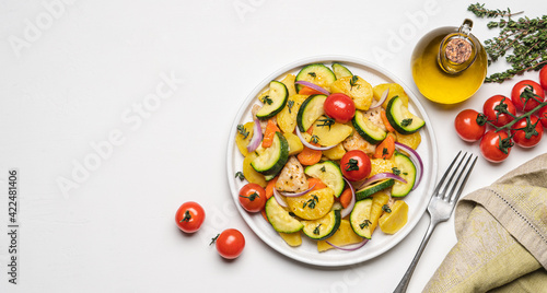 Baked vegetables and meat in plate on white background. Cooked dish of Potatoes, zucchini, carrots, onions, tomato and chicken