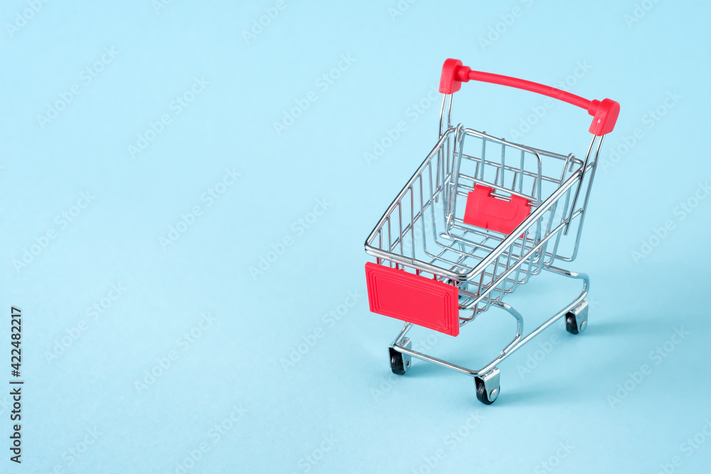 Empty red shopping cart on blue background, mini metal cart isolated on yellow background, copy space for text