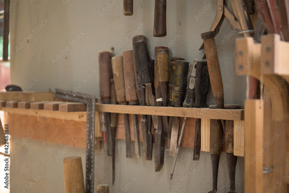 A rack full of chisel and handtools for wood carving in a workshop 