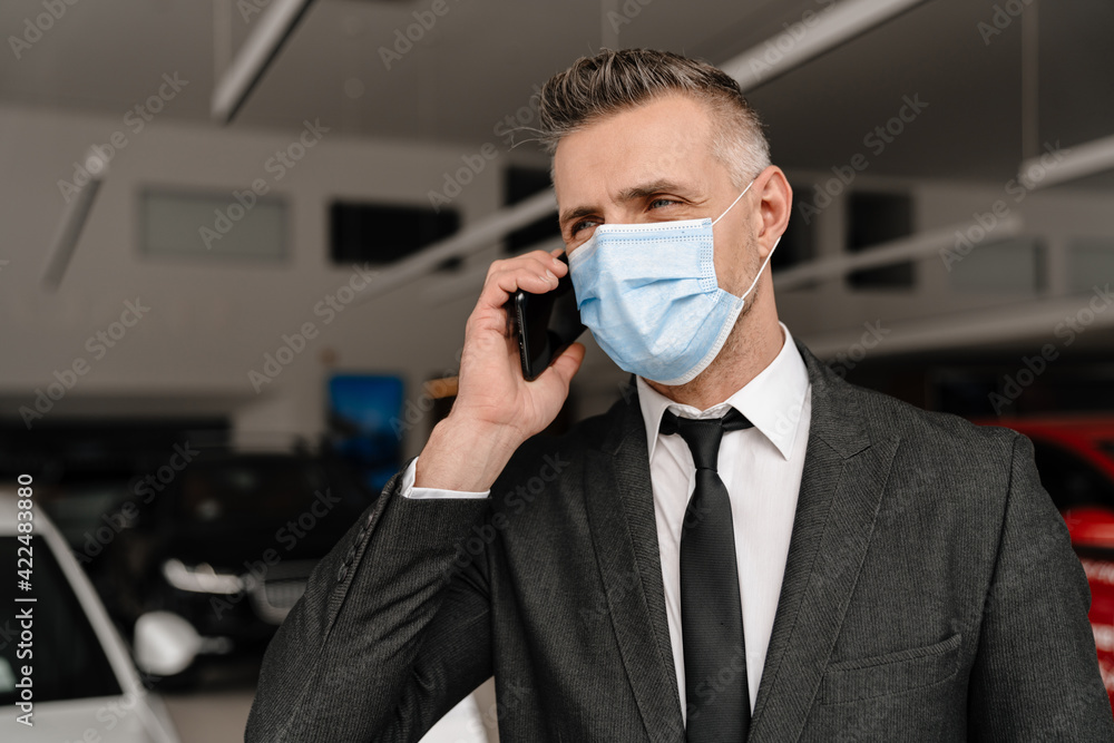 White man in face mask talking on cellphone while choosing car White man in face mask talking on cellphone while choosing car
