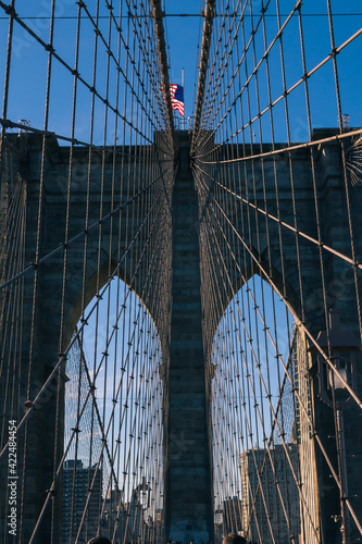 A vertical view of the American Flag flying over the Brooklyn Bridge in New York City USA