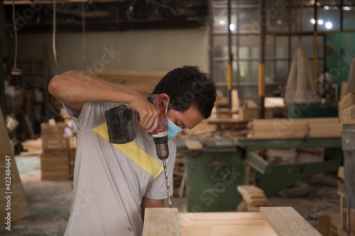Close-up of carpenter using electric drill in workshop and routing out holes Cabinetmaker drilling wood on table. Joinery work on the production and renovation of wooden furniture. Small Business