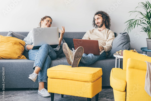 Couple using laptop while sitting on sofa at home.