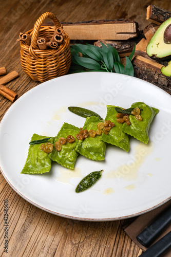 Green dumplings with spinach and sauce on a large white plate 