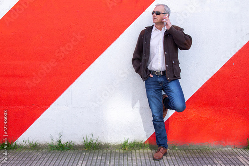 adult man leaning on the wall using the phone