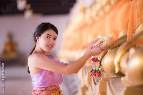 The girl in Thai dress presents a garland for the Lord Buddha.preserving the good culture of Thai people during Songkran festival. Thai New Year, Family Day in April © NITIKAN T.