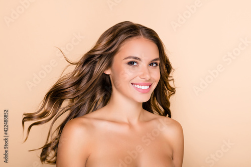 Photo of young happy positive smiling lovely girl with flying hair wear no clothes isolated on beige color background
