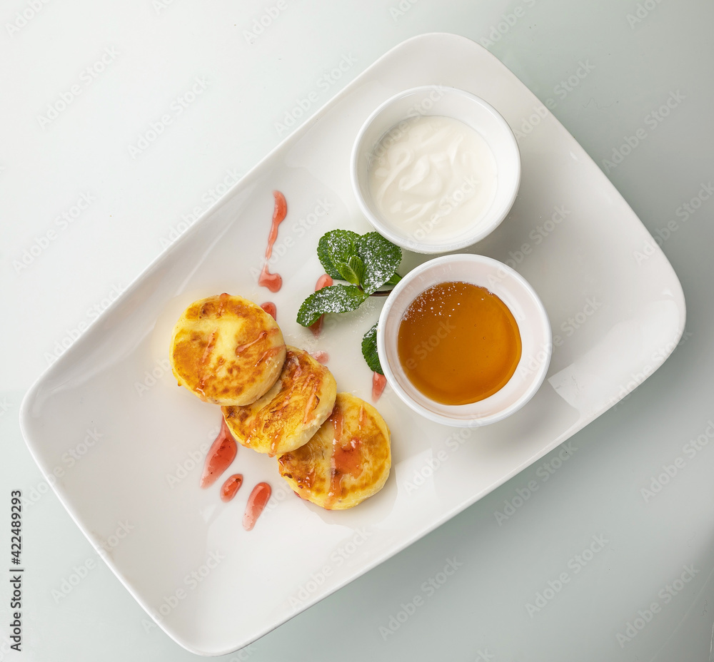 Cheesecakes with sour cream and honey on a white table
Cheesecakes with sour cream and honey on a white table