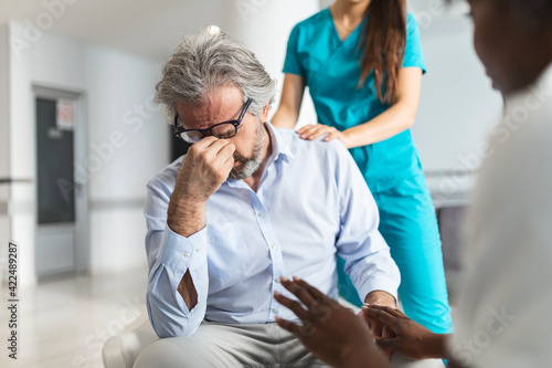 Doctor consoling upset man in hospital waiting room. Patient receiving bad news, he is desperate and crying, Doctor support and comforting her patient with sympathy. Don't worry is not so bad