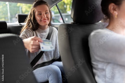 female passenger giving money to taxi car driver © Syda Productions
