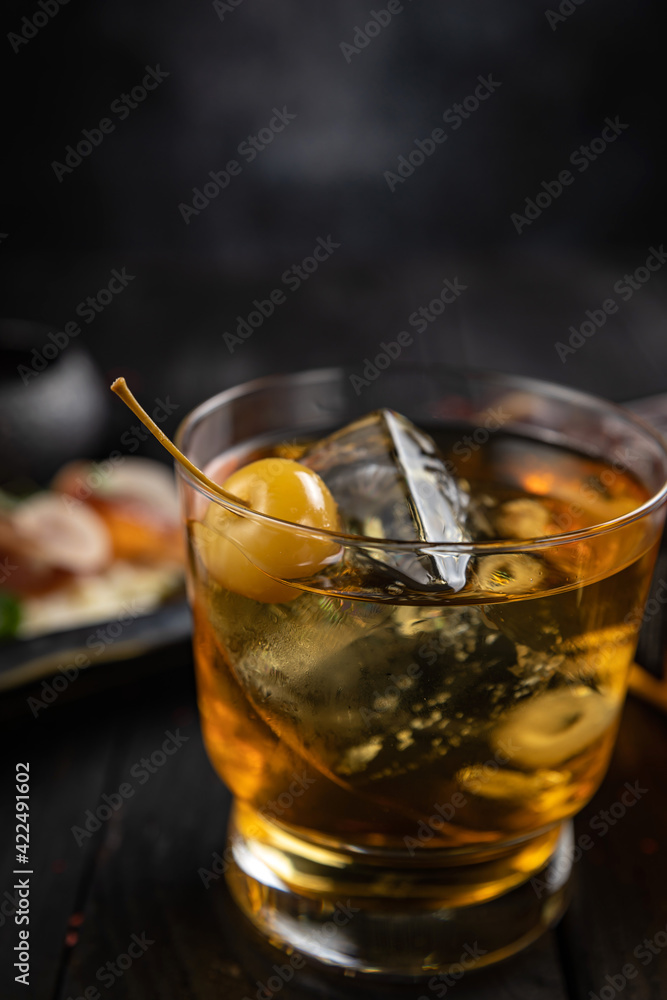 Cocktail with ice and cherry on a dark table. Snacks for a cocktail
Cocktail with ice and cherry on a dark table. Snacks for a cocktail