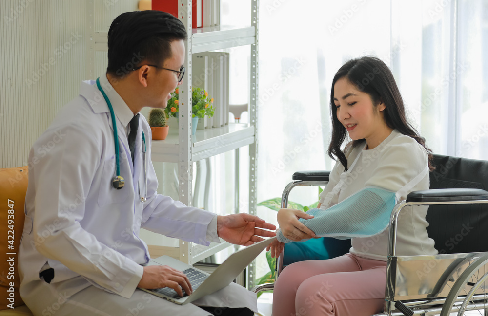 Doctor helping Asian patient with arm sling Doctor helping Asian patient with arm sling