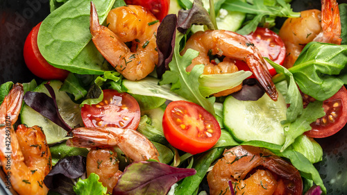 Shrimps salad, cherry tomatoes, cucumber and mixed leaves. Healthy food. Clean eating. Food recipe background. Close up