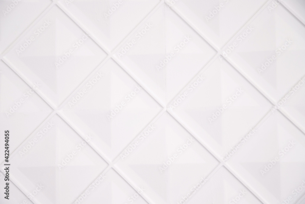 White wall decorated with diamonds. Geometric shapes in the interior. Stylish and voluminous background. White wall decorated with diamonds. Geometric shapes in the interior. Stylish and voluminous background.
