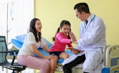 Cute and adorable Asian little girl sitting on patient bed in hospital and hi-five hand touching with doctor to compromise that she will surely get well after cure process photo