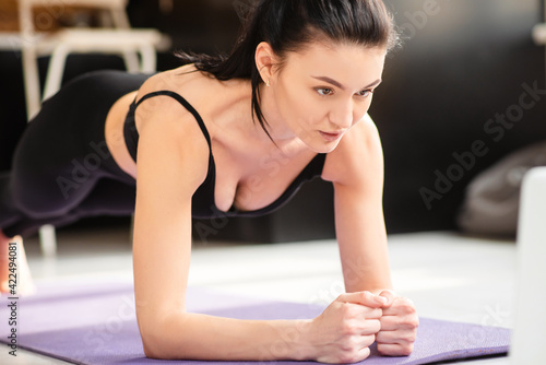 Strong woman training at home and using laptop