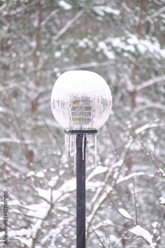 Obraz na płótnie The snow-covered street lamp during the snowfall in a European city. w salonie