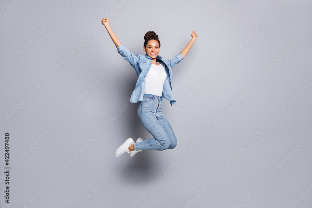 Photo portrait full body view of dark skin girl celebrating with raised fists jumping up isolated on clear grey colored background