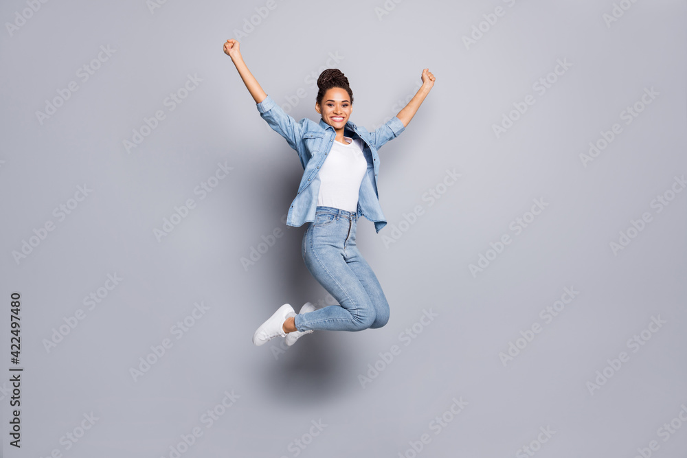Photo portrait full body view of dark skin girl celebrating with raised fists jumping up isolated on clear grey colored background Photo portrait full body view of dark skin girl celebrating with raised fists jumping up isolated on clear grey colored background