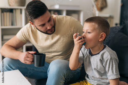 Tableau sur toile boy using asthma pump. father is sitting beside him