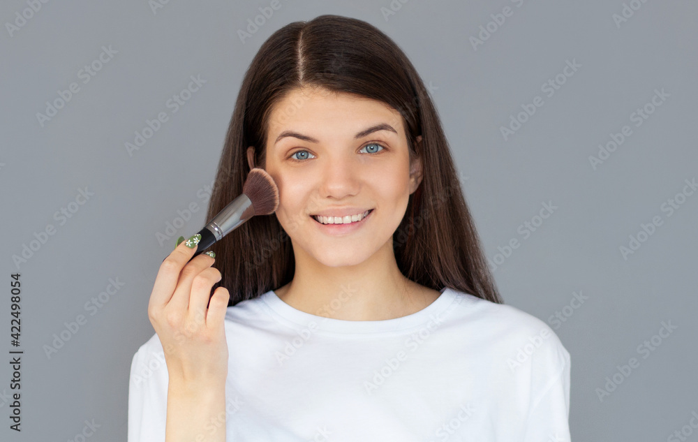 Portrait of attractive young adult woman with make up brush in her hand Portrait of attractive young adult woman with make up brush in her hand