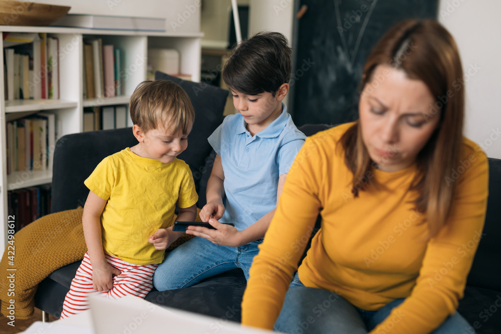 mother working from home. children are playing in background mother working from home. children are playing in background