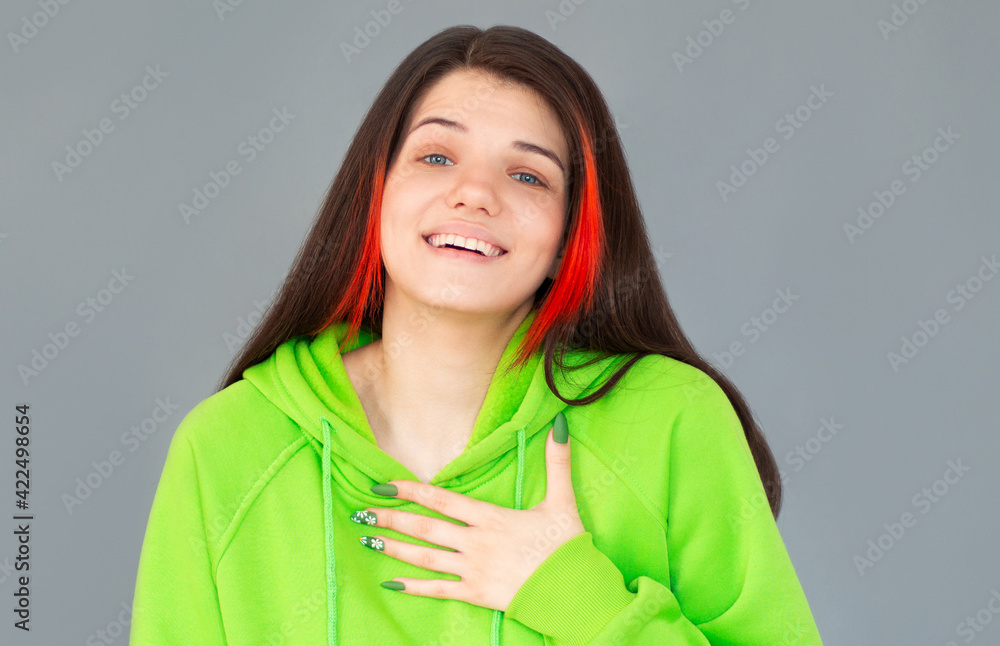 Kind girlfriend keeps hand on chest, expresses friendly manners, dressed in casual white t-shirt, being touched by heart piercing story, isolated over gray background. Thankful woman Kind girlfriend keeps hand on chest, expresses friendly manners, dressed in casual white t-shirt, being touched by heart piercing story, isolated over gray background. Thankful woman