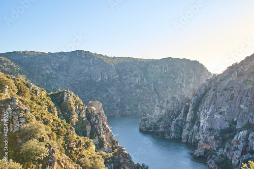 Three rocky mountains with cliffs and a river at sunset