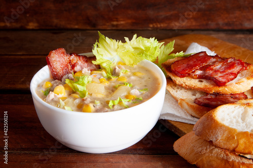 Corn chowder soup with bacon. Brown wooden background. Close-up view