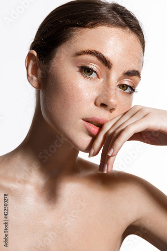 Skin care. Woman with beauty face touching healthy facial skin portrait. Beautiful smiling girl model with natural makeup touching glowing hydrated skin on white background closeup