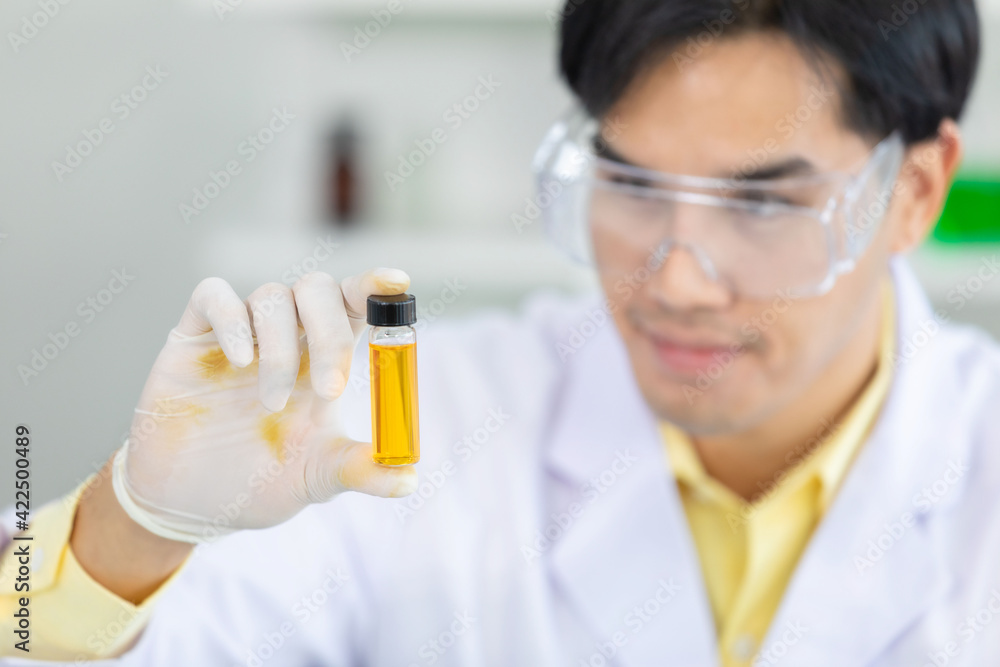 Close up hand. Asian scientist holds a scientific liquid in a beaker. protective equipment protective clothing, goggles, gloves inside the scientific laboratory. Concept medical coronavirus covid19. Close up hand. Asian scientist holds a scientific liquid in a beaker. protective equipment protective clothing, goggles, gloves inside the scientific laboratory. Concept medical coronavirus covid19.