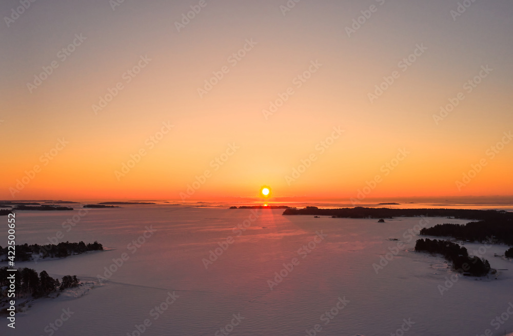 Aerial view of sunrise over the ice-covered Baltic Sea in winter.