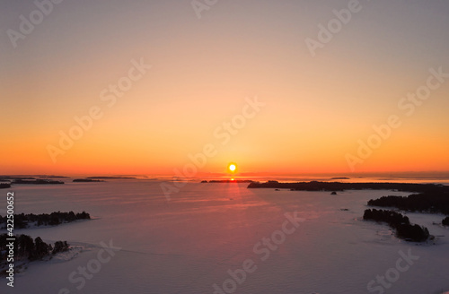 Aerial view of sunrise over the ice-covered Baltic Sea in winter.