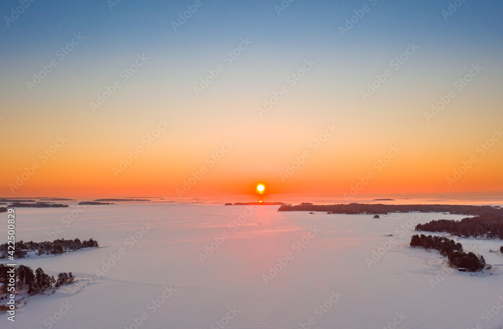Aerial view of sunrise over the ice-covered Baltic Sea in winter.