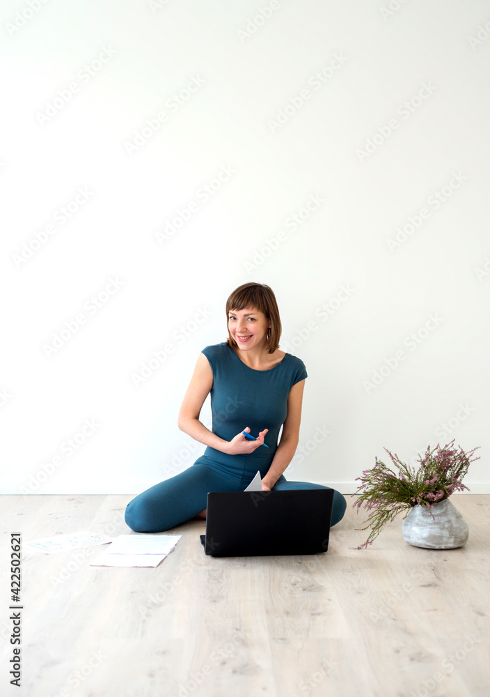 Fototapeta premium Woman sitting on floor next to laptop and working