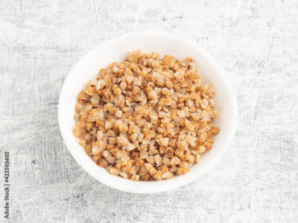 Buckwheat in ceramic bowl on white concrete background Buckwheat in ceramic bowl on white concrete background