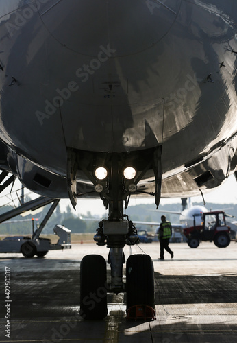 Jet's nose landing gear at the airport parking area. Aircraft service check before flight. 