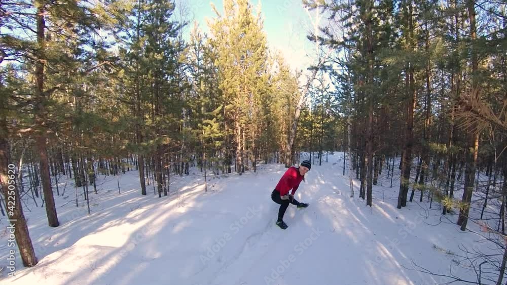 Warm up and jogging in the winter forest.  2 Shots. 
1. A man stretches his legs, spine and shoulders before jogging. 2. He runs along a snowy forest path.
Wide shots. Pan.