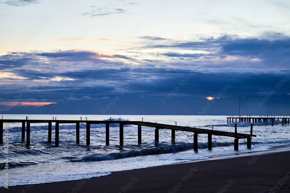 View from beach to water of sea, waves with white foam, pierce and sky with clouds in a nice evening. View from beach to water of sea, waves with white foam, pierce and sky with clouds in a nice evening.