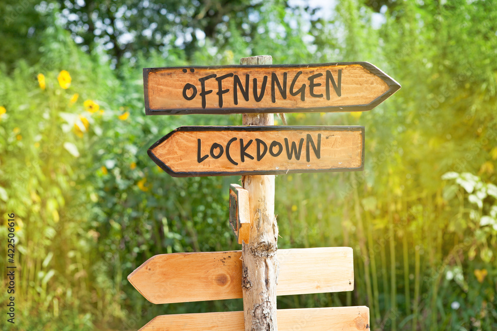 Wooden direction sign with the German word Öffnungen (openings) and Lockdown