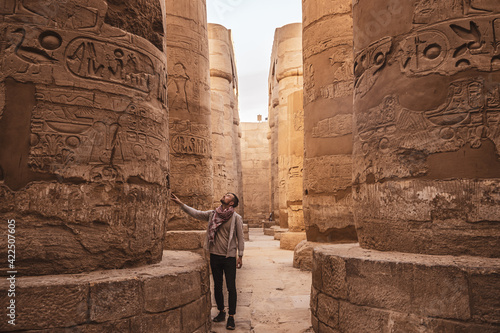 Young man gazing up in wonder at the massive columns at Karnak Temple in Luxor Egypt photo