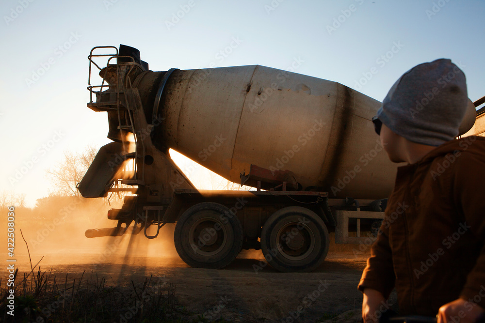 Construction equipment. A concrete mixer is driving along a country road.