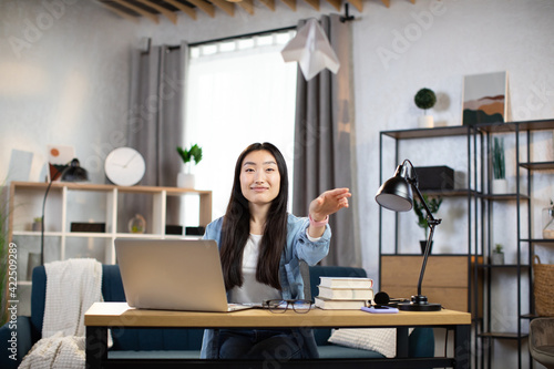 Smiling female freelancer playing with paper plane while working from home. Attractive asian woman taking break during working time.