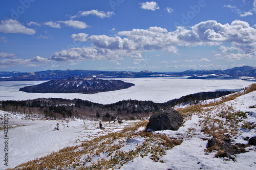 冬の青空と白く氷に覆われた屈斜路湖を望む美幌峠の風景。